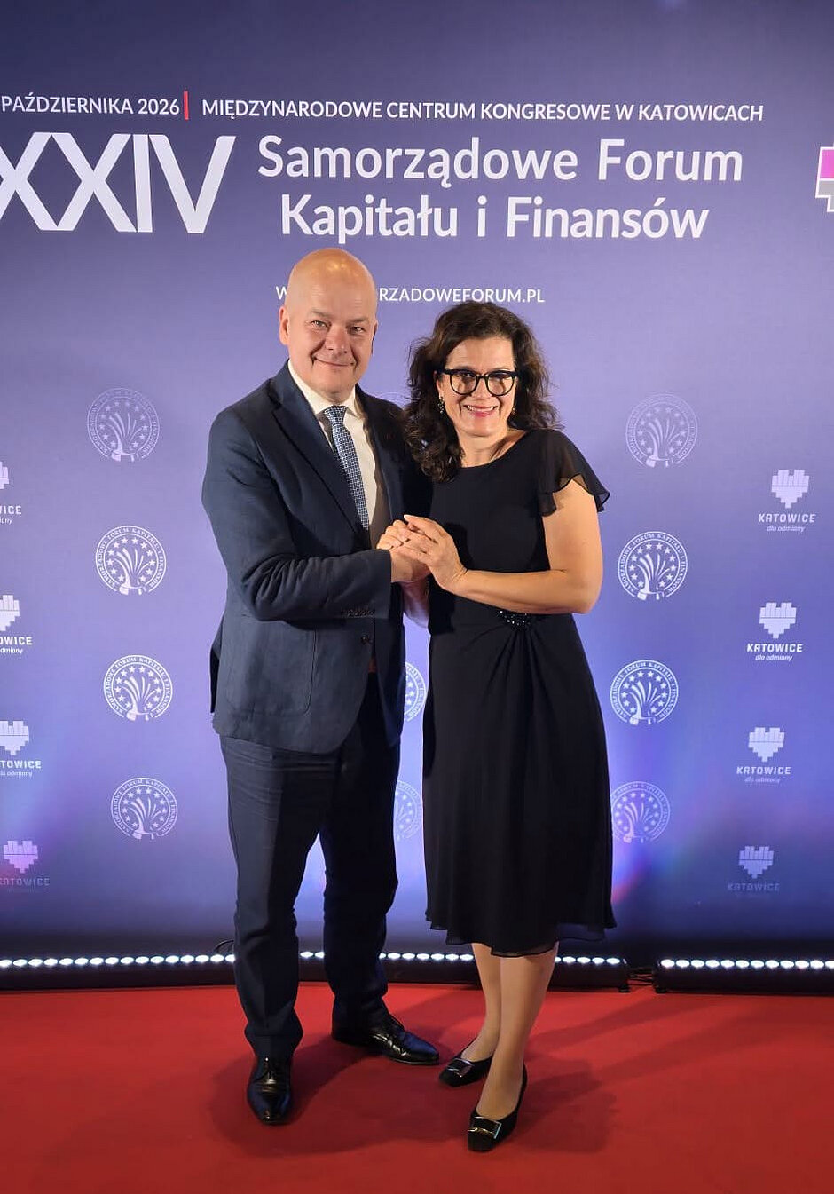 Zdjęcie mężczyzny po lewej, który składa gratulacje kobiecie po prawej