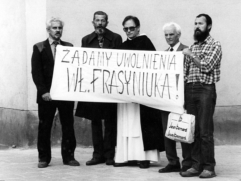 Stare zdjęcie czarno-białe, które przedstawia pięciu - trzymają transparent z napisem: Żądamy uwolnienia Wł. Frasyniuka 
