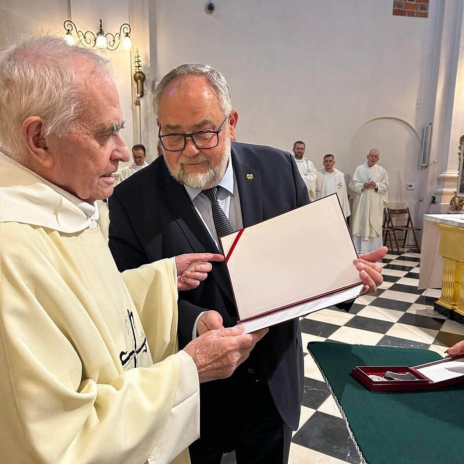 Stoją i rozmawiają dwaj mężczyźni, ten po lewej ubrany w dominikański habit