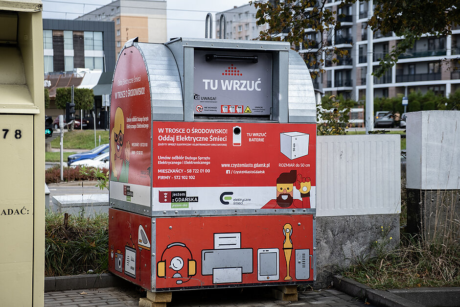 Czerwony pojemnik na elektroodpady na osiedlu w mieście.