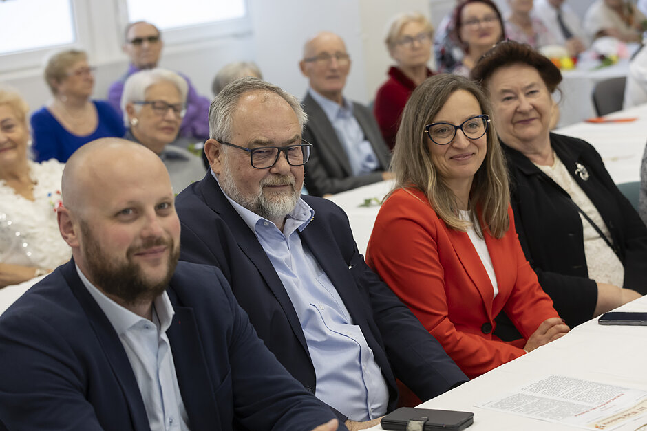 na zdjęciu dwóch mężczyzn i dwie kobiety siedzące przy stole z białym obrusem
