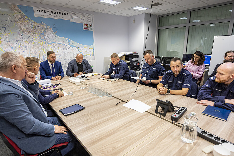 Zestawione ze sobą stoły i mężczyźni, którzy przy nich siedzą