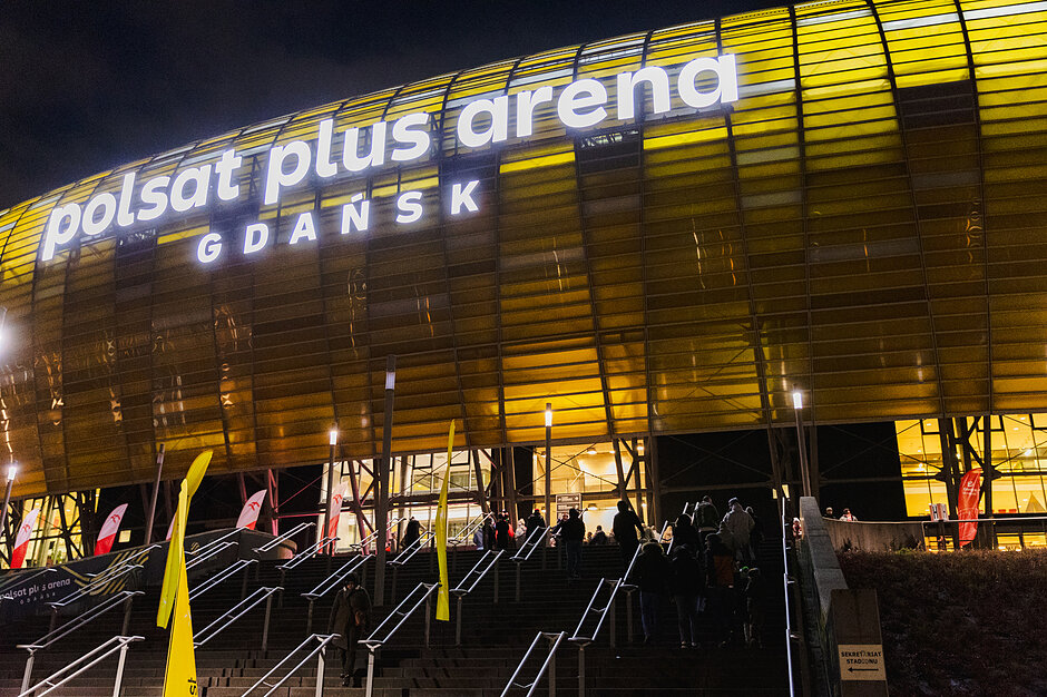 Zdjęcie rozjarzonej na kolor bursztynowy korony stadiony polsat plus arena gdańsk - zdjęcie zrobione wieczorową porą