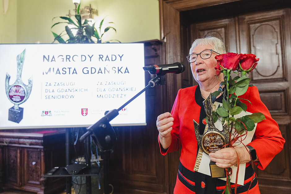 na zdjęciu starsza kobieta w czerwonym kostiumie