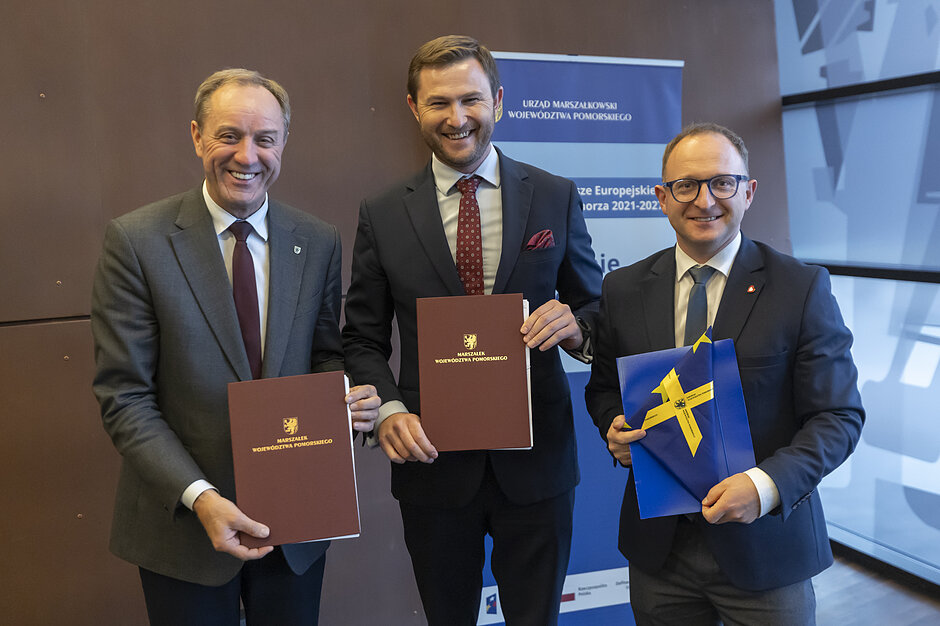 na zdjęciu trzech mężczyzn w garniturach granatowych, stoją, pozują do zdjęcia