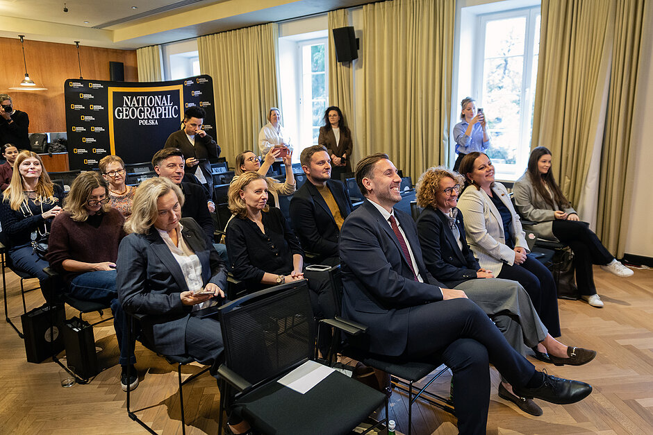 Ludzie siedzą na konferencji prasowej.