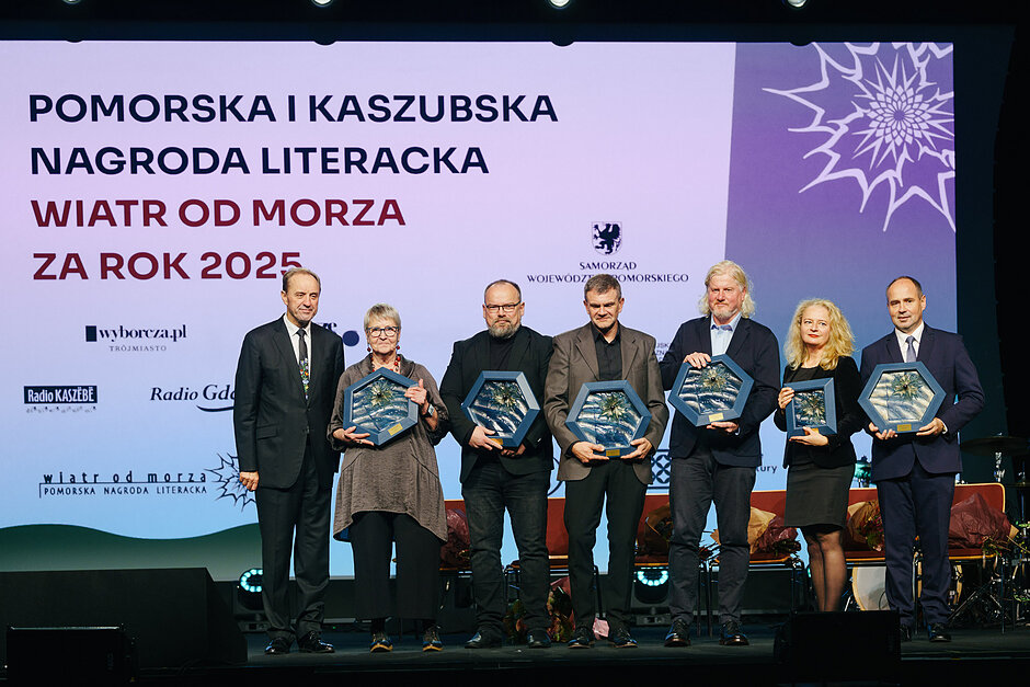 Mężczyźni i kobiety stojący w rzędzie, w ręku trzymają statuetki
