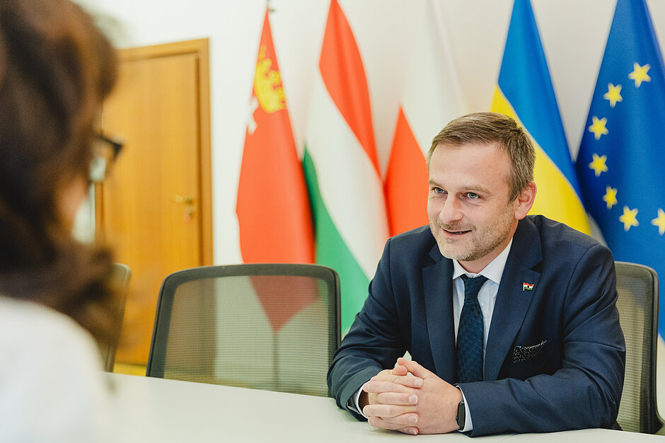 Mężczyzna w średnim wieku siedzący naprzeciwko prezydent Dulkiewicz