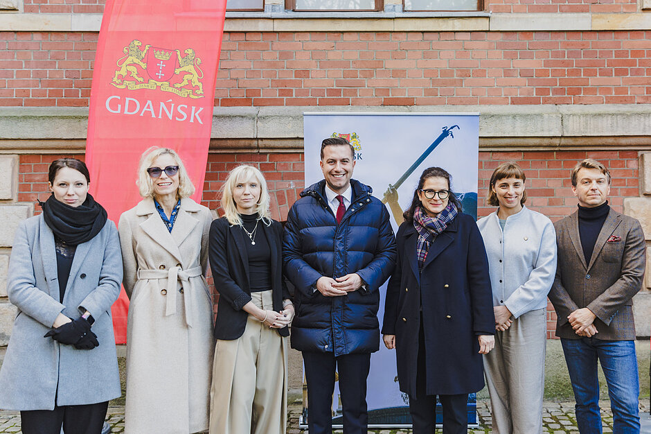 do zdjęcia pozuje grupa siedmiu osób, stoją w jednym rzędzie