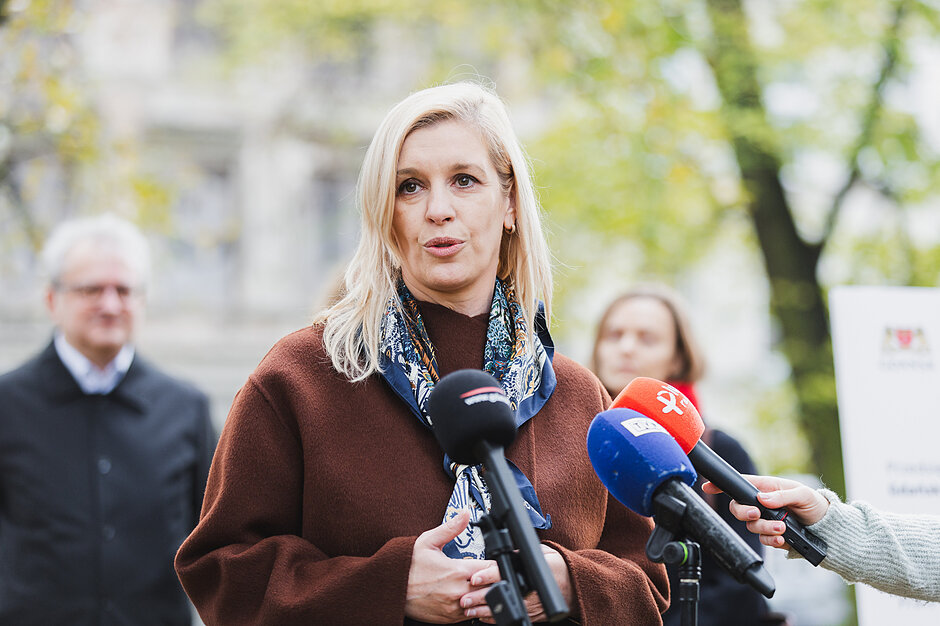 na zdjęciu wiceprezydent gdańska emilia lodzińska w brązowym płaszczu, mówi do mikrofonów