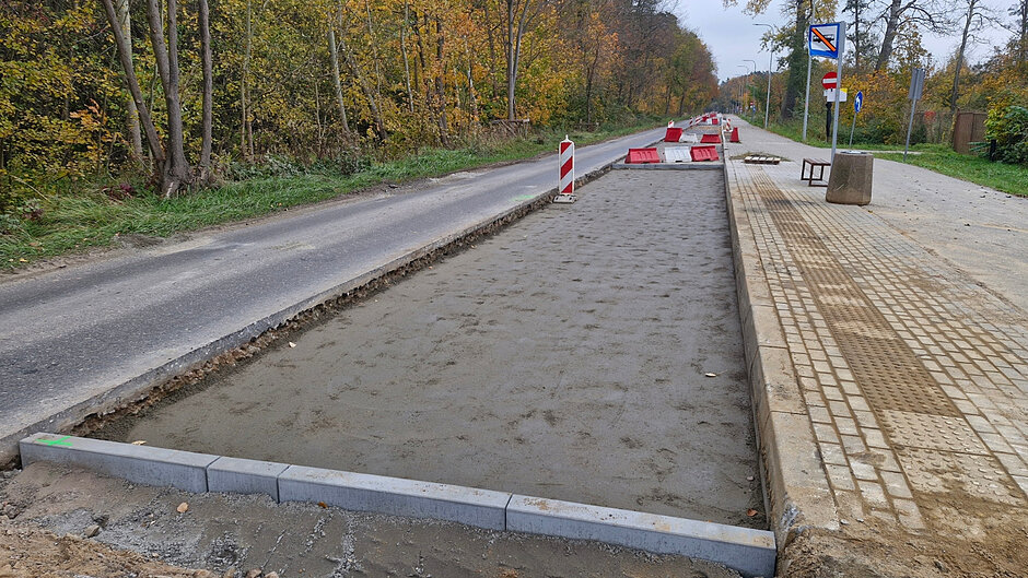 na zdjęciu remontowana ulica, jej środkowa część jest wymieniana, widać pierwszą warstwę nowej nawierzchni 