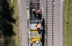 zdjęcie z lotu ptaka, na torach kolejowych pojazd techniczny z platformą, na której pracują robotnicy w kasakch 