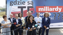 Kilka kobiet i mężczyzn na konferencji prasowej w tle duży plakat z napisem Gdzie są te miliardy złotych dla Polski???