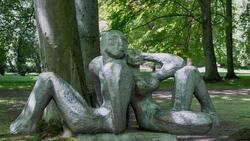 rzeźba dwie postaci - kobieta i mężczyzna - siedzą na podeście opierając się o siebie plecami