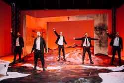 pięcioro aktorów na oświetlonej na czerwono scenie
