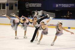 Pięć kobiet i jeden mężczyzna jadą na lodzie, jedna noga w powietrzu wyciągnięta do tyłu