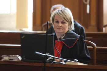 Kobieta w prokuratorskiej todze siedząca na sali rozpraw w sądzie