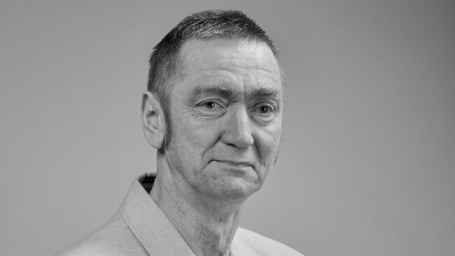 czarnobiały portret mężczyzny w średnim wieku. Zdjęcie zostało zrobione w studiu, mężczyzna ma na sobie marynarkę.