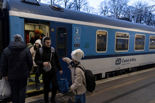 Z wagonu kolejowego na peron wysiadają podróżni.