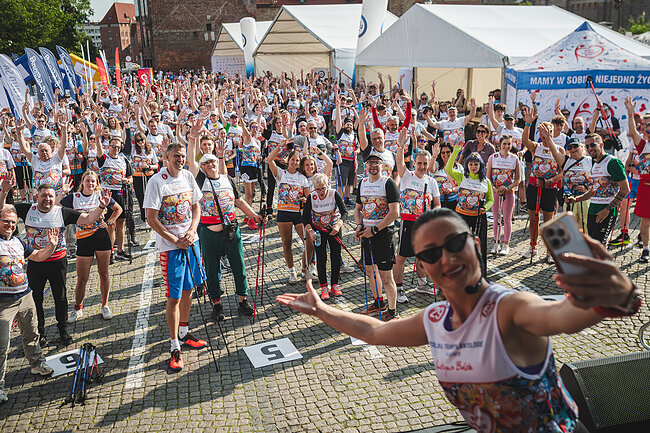27. Bieg po Nowe Życie - rozgrzewka. Grupa ludzi w sportowych ubraniach rozgrzewa się przed biegiem 