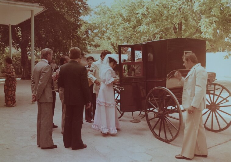 stara kolorowa fotografia, kareta z której wysiada kobieta w białej sukni, kilka osób wokół