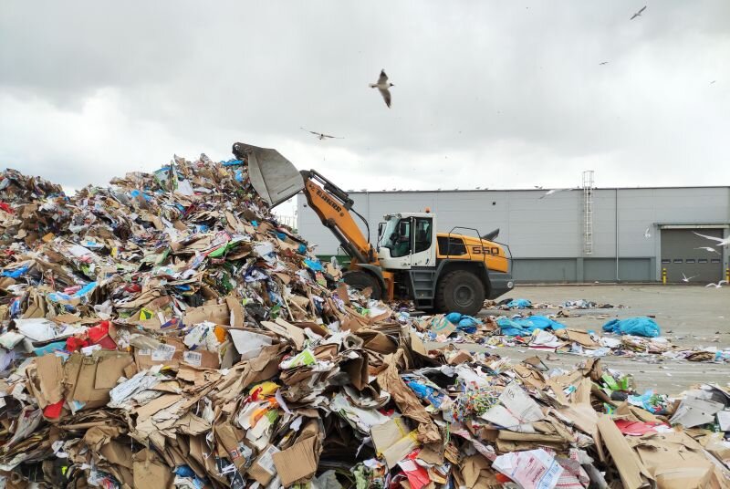 koparka przenosi tony makulatury z jednego miejsca na drugie, pryzma papierów w powietrzy mewy