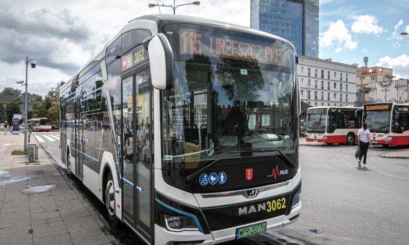 nowoczesny autobus stoi na pustym placu, w tle szklany wieżowiec