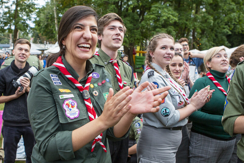 Uśmiechnięte harcerki i harcerze, klaszczą, ich wzrok skierowany na prawo i do góry 