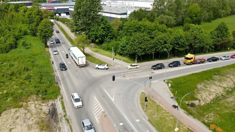 Widok z góry: skrzyżowanie ulic, na nich samochody. Po bokach drzewa