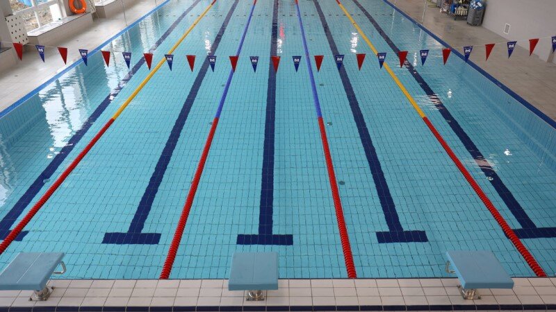 Widok na pływalnię baseny. Niebieskawe kafelki, pływalnia wypełniona wodą. Niw ma ludzi