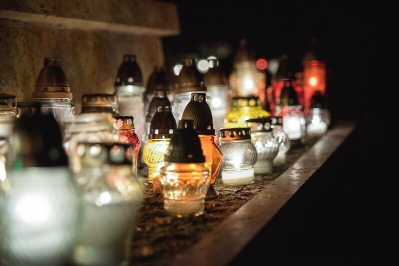 Zdjęcie przedstawia płonące znicze na gdańskich grobach