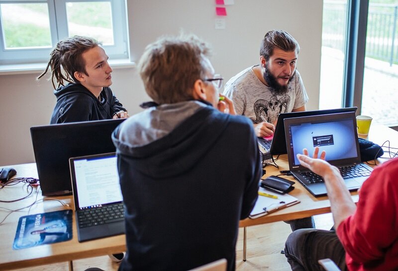 młodzi mężczyźni przy stole, przy laptopach