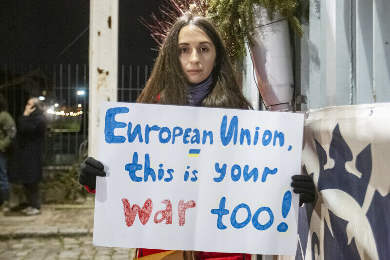 dziewczyna trzyma nocą transparent z napisem European Union This is Your War Too