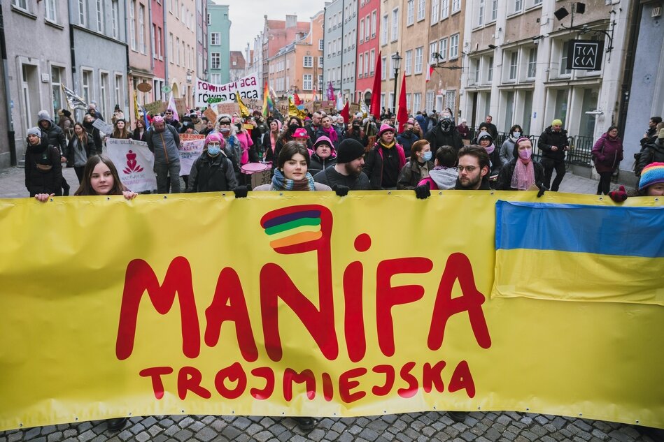 na zdjęciu tłum osób uczestniczących w manifestacji, na pierwszym planie ogromny żółty baner z napisem trójmiejska manifa