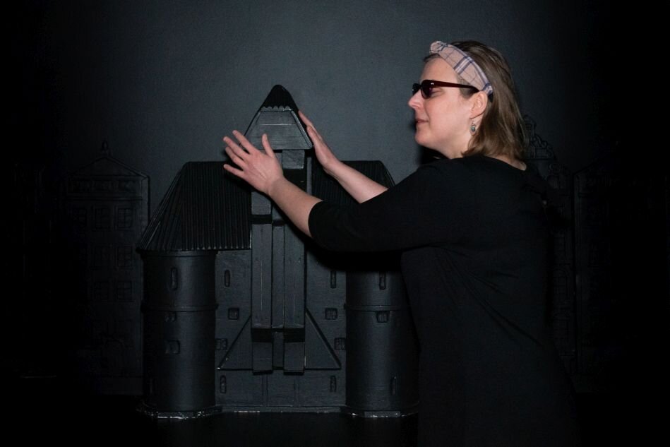 kobieta w ciemnych okularach, dotyka dłońmi miniaturę gdańskiej budowli Żurawia