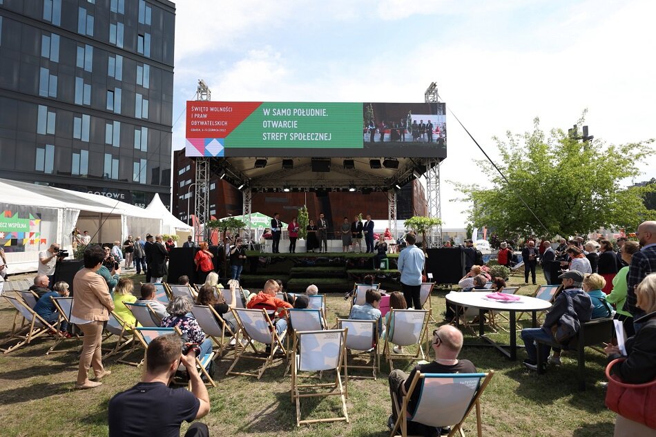Scena z napisem Strefa Społeczna, przed nią ludzie na leżakach i stojący