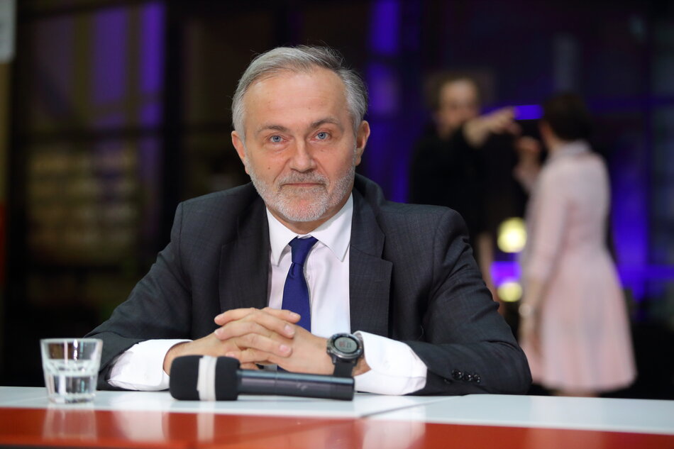 opisany mężczyzna na zdjęciu, siedzi za stołem