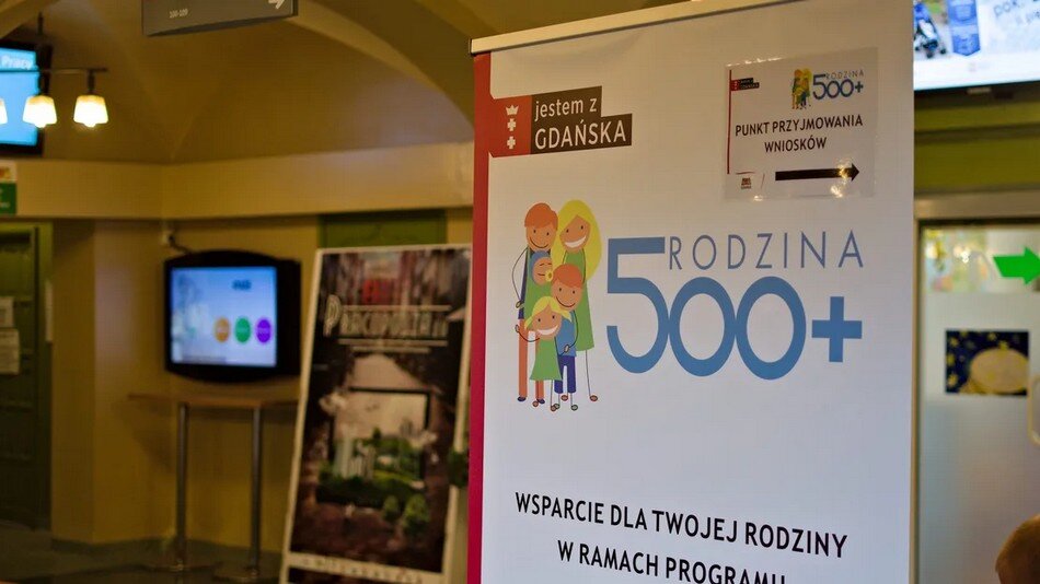 Pomieszczenie w urzędzie, plansza z napisem: Rodzina 500+