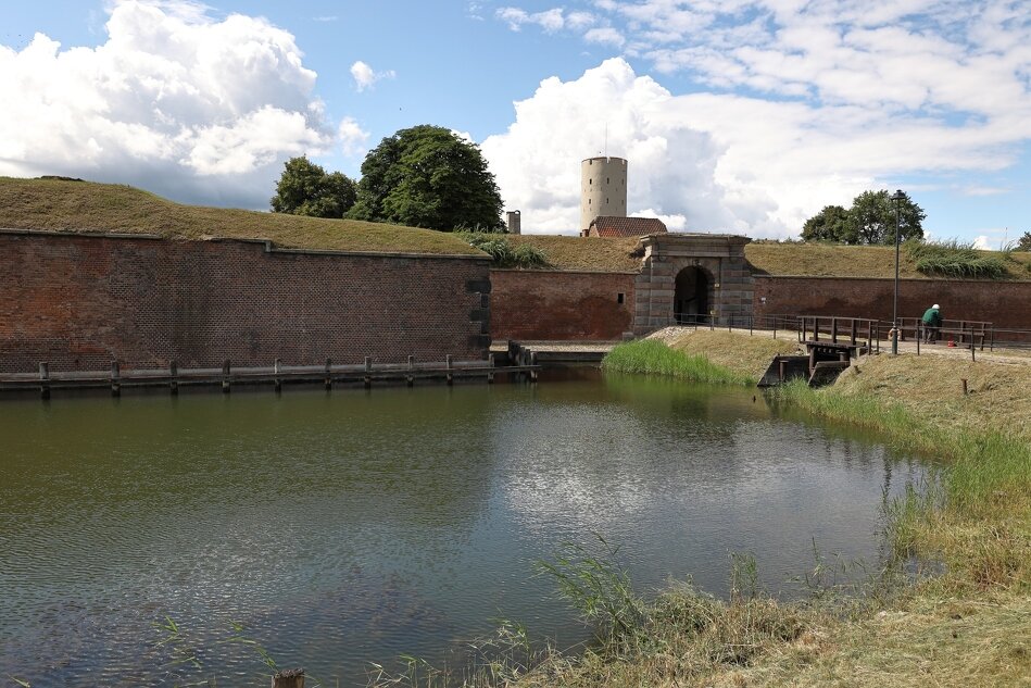 Widok zabytkowej Twierdzy Wisłoujście z ceglanym murem i zbiornikiem wodnym
