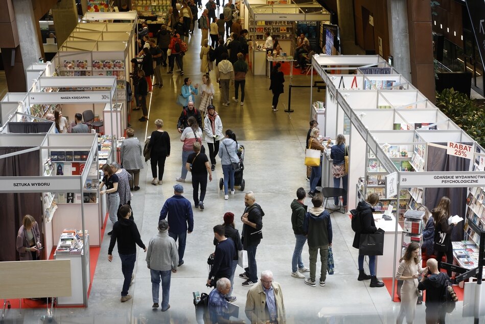 duży korytarz w nowoczesnym wnętrzu, dużo ludzi chodzi między stoiskami z książkami
