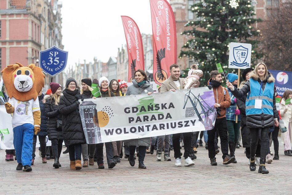 Grupa uśmiechniętych ludzi idąca w gdańskiej paradzie wolontariatu