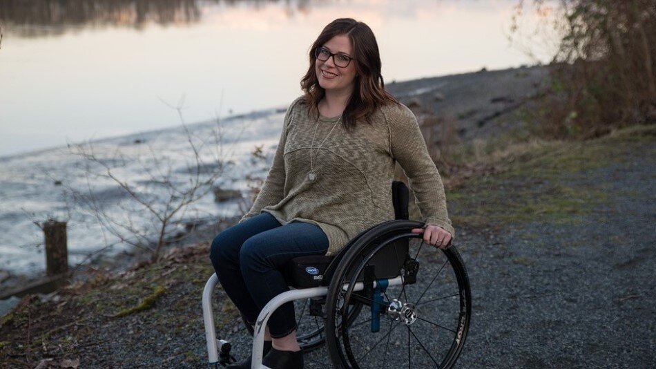Uśmiechnięta kobieta siedząca na wózku inwalidzkim nad brzegiem wody