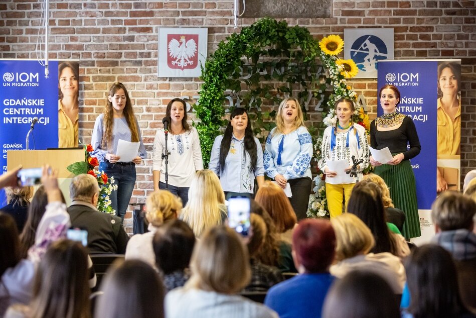 sześć młodych kobiet w strojach ludowych stoi i śpiewa