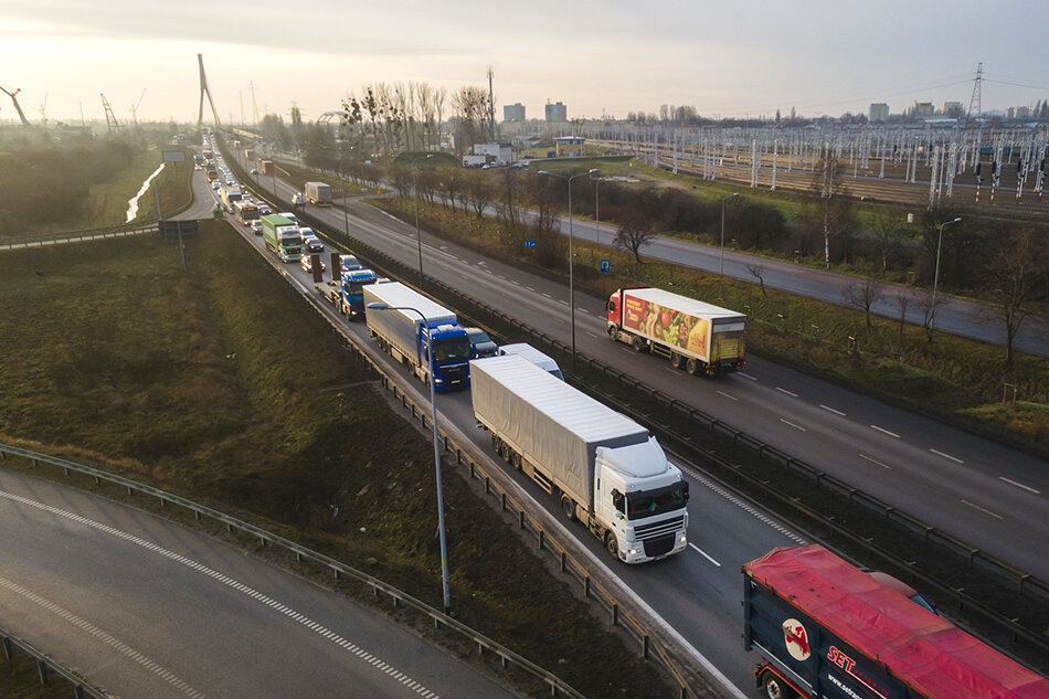 panoramiczny widok na dwupasmową jezdnię. Na pierwszym planie widoczny sznur pojazdów w tle duży most