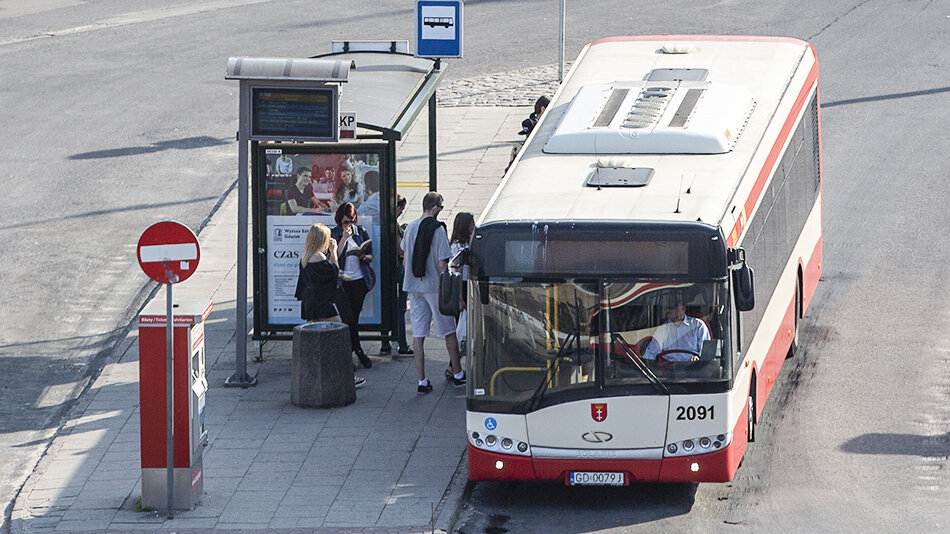 ludzie wsiadający do autobusu na przystanku