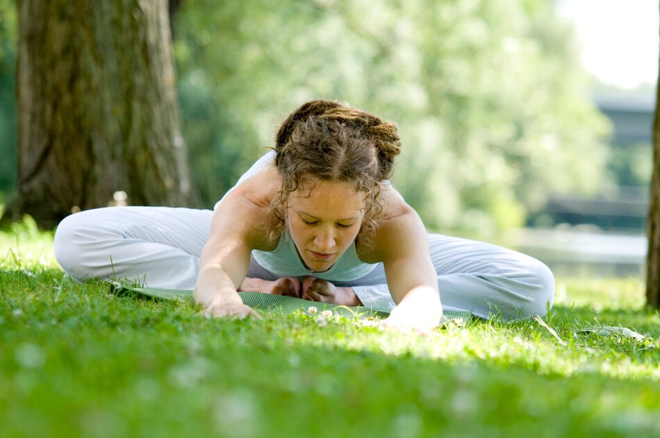 młoda kobieta ćwicząca jogę na trawniku