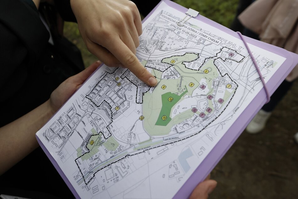 na zdjęciu wydrukowana niewielka mapka, widać też ludzką dłoń, która wskazuje coś palcem na mapie