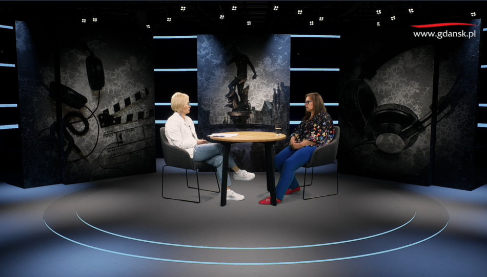 na zdjęciu dwie kobiety w studiu telewizyjnym, siedzą przy stoliku, w fotelach, rozmawiają 