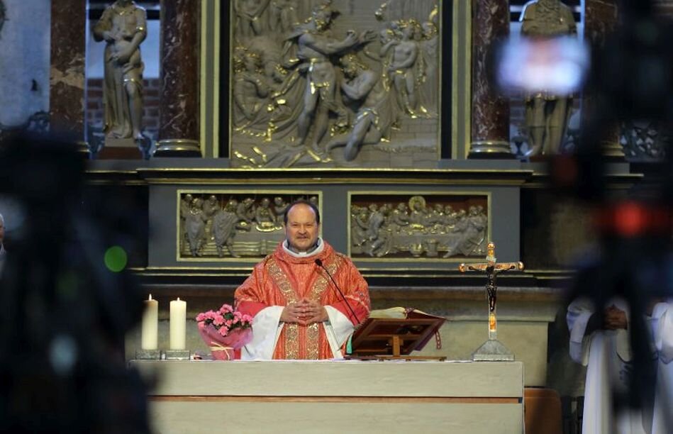 kapłan w czerwonych szatach liturgicznych stoi za ołtarzem