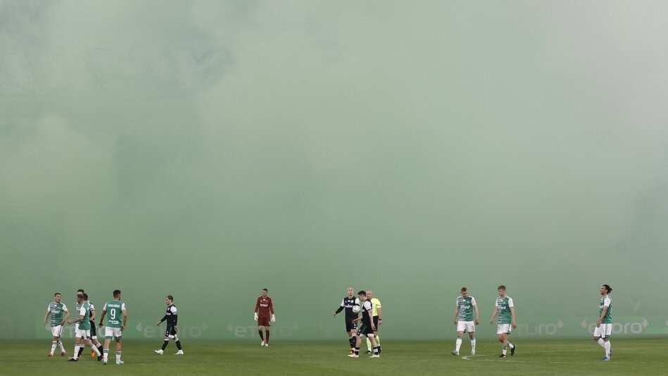 Piłkarze na murawie nad nimi wielka dymna mgła